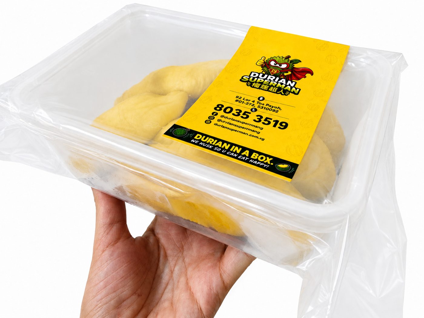 A hand holding a 400g Durian Superman box — dehusked durian flesh vacuum sealed under the yellow label